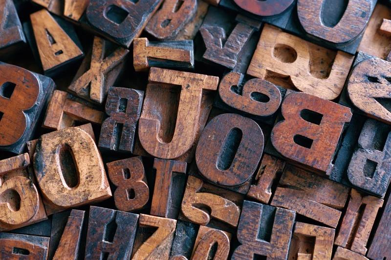Vintage wooden letterpress type blocks densely arranged in a pile