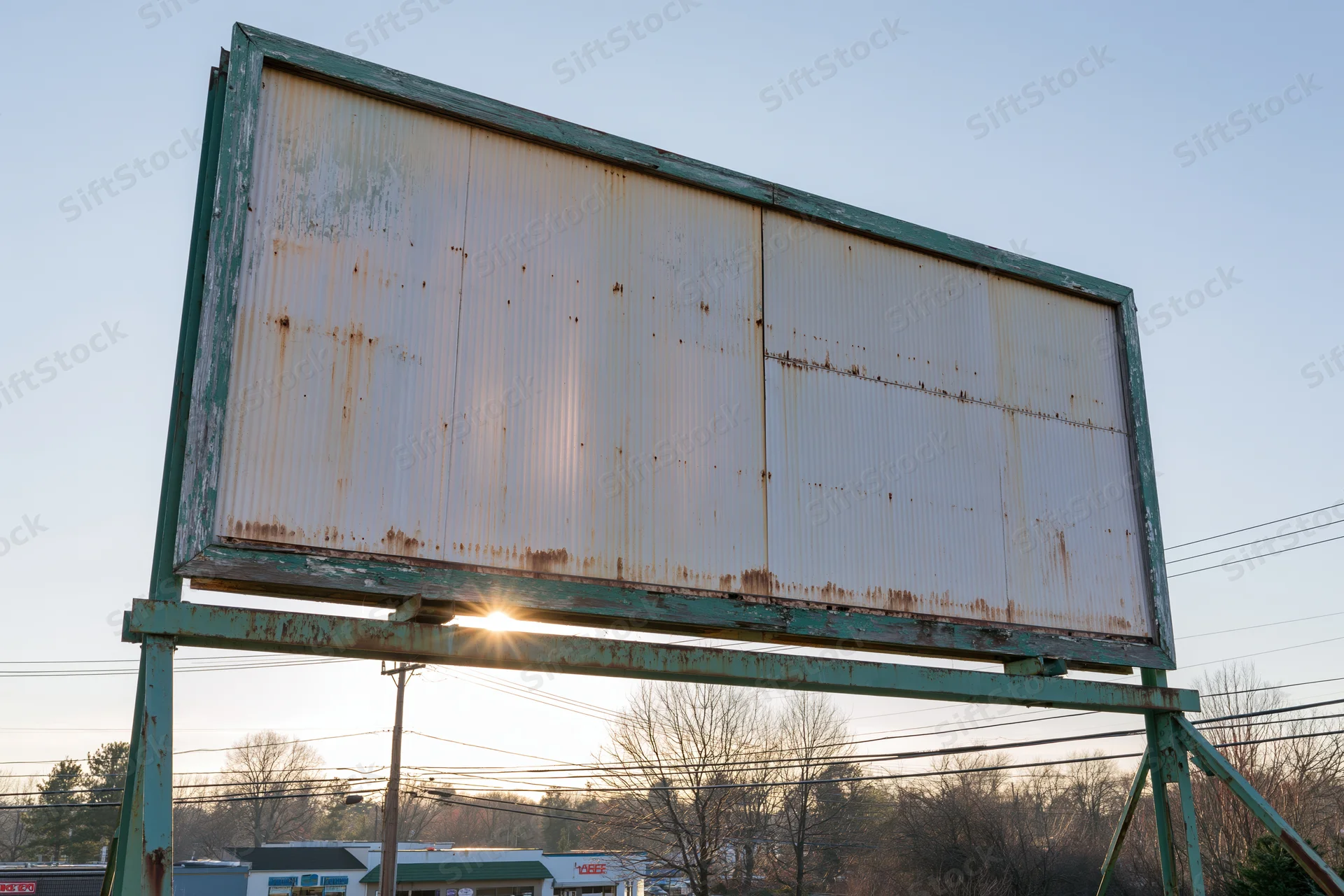 Weathered roadside billboard with empty metal letterboard against sunset sky