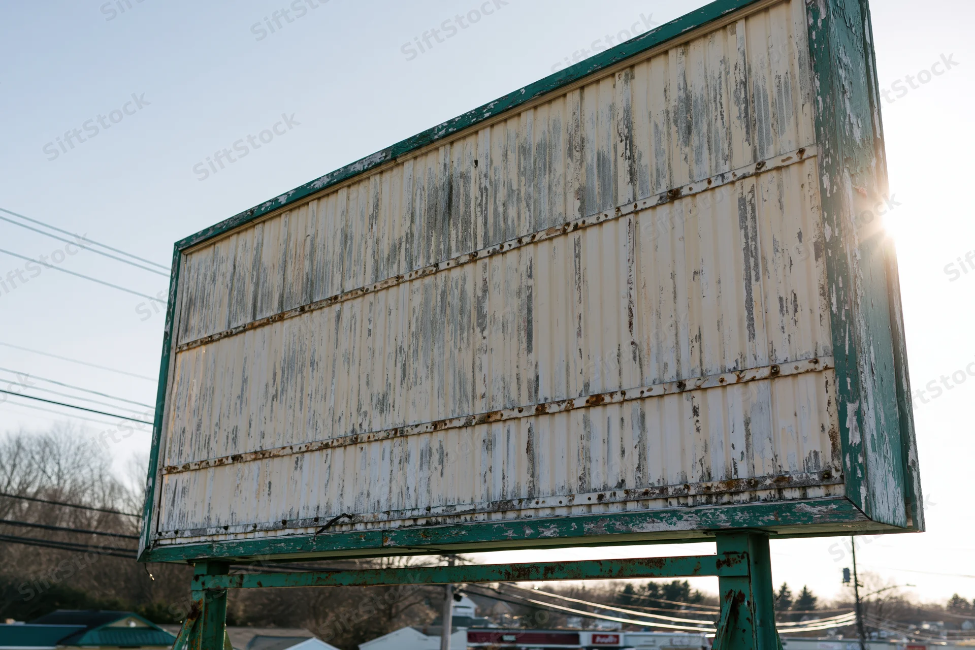 Weathered roadside billboard with peeling paint and empty letterboard under bright sun