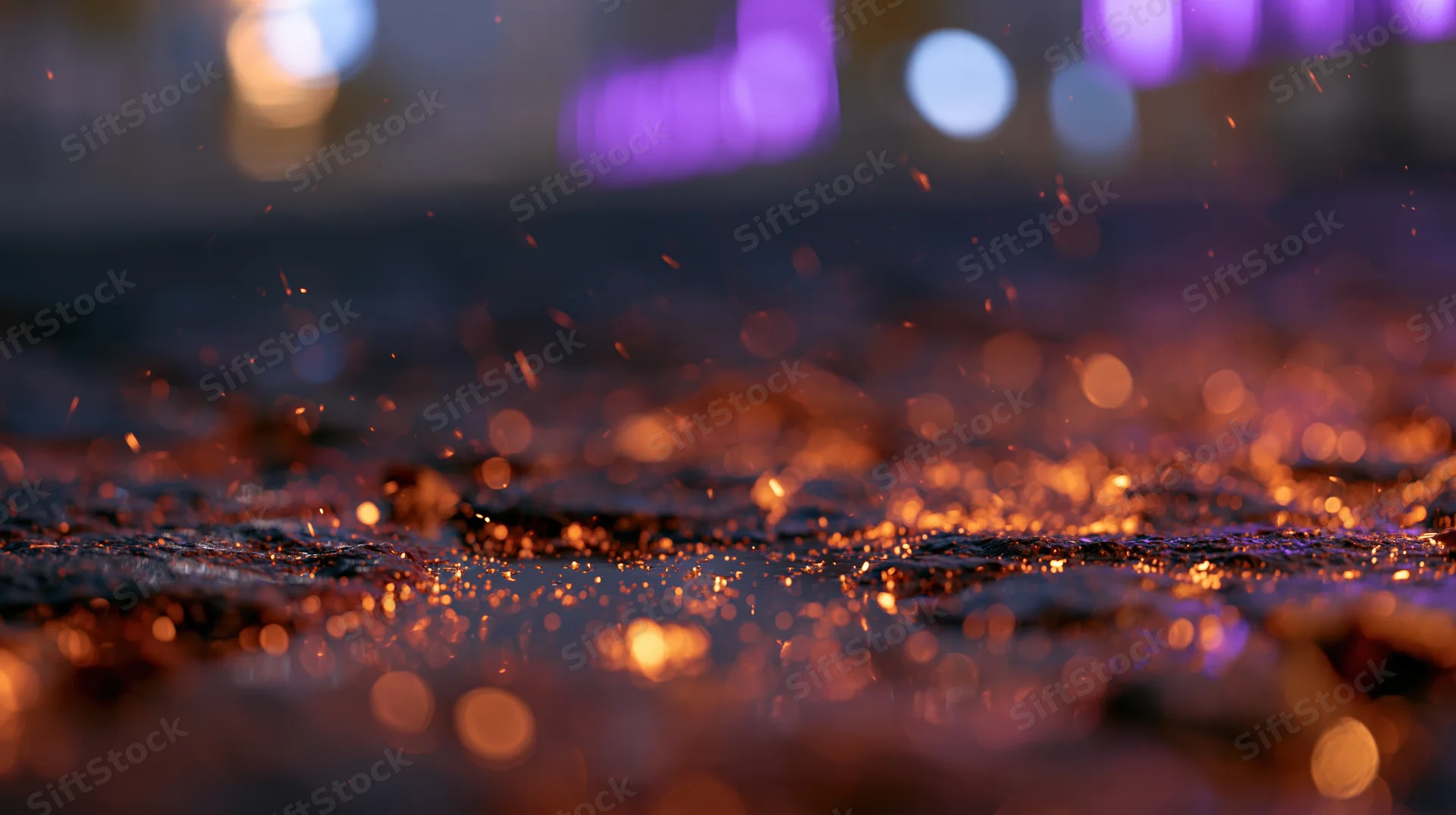 Glowing embers scattered across wet cobblestone pavement at night with blurred city lights in background