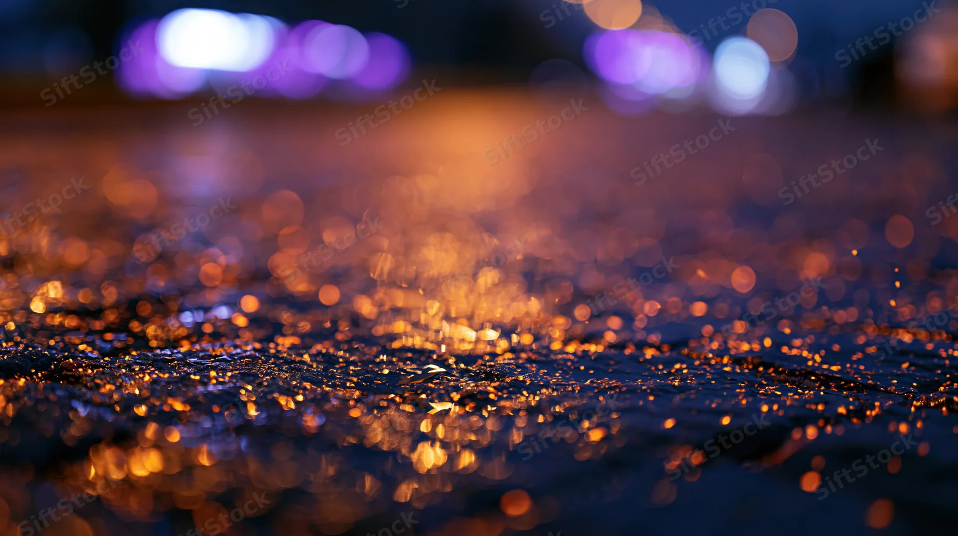 Wet pavement reflecting city lights at night with bokeh effect