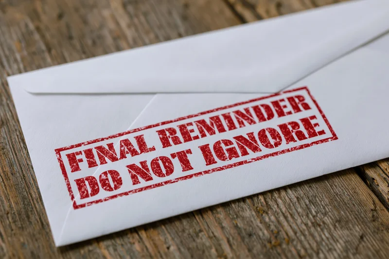 White envelope with red final reminder stamp on wooden surface