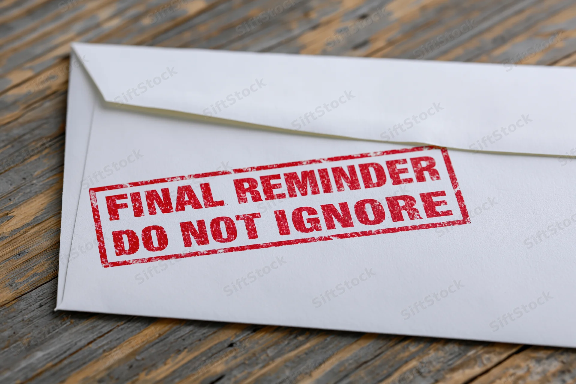 White envelope with red final reminder stamp on wooden surface