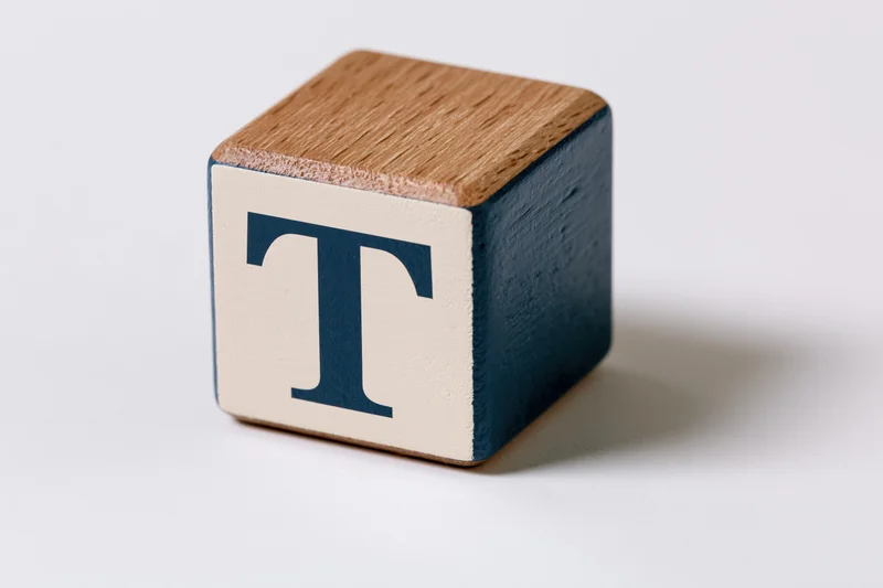 Wooden alphabet block with letter t on white background