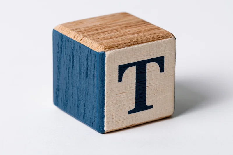 Wooden alphabet block with letter t on white background