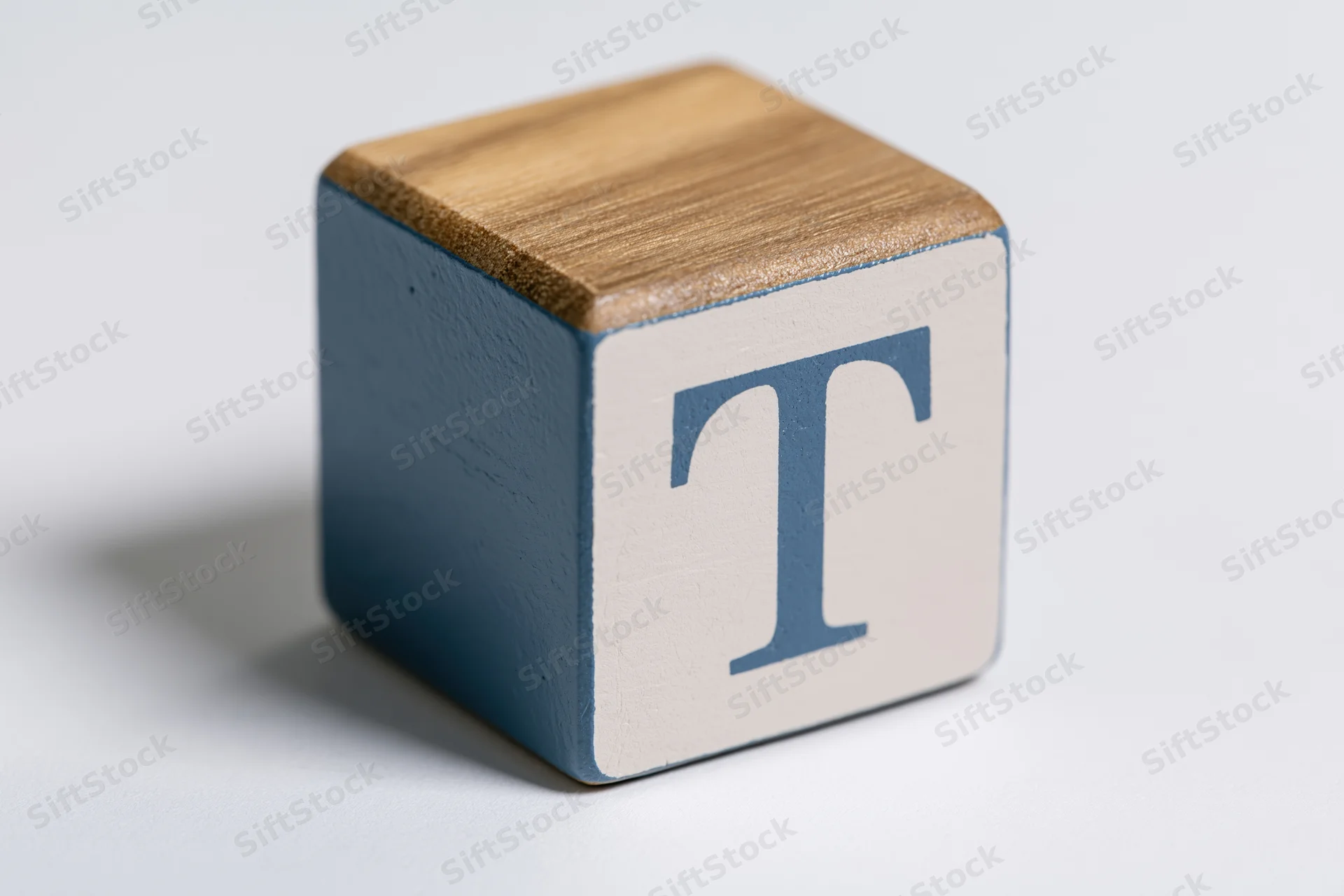 Wooden alphabet block with letter t on white background