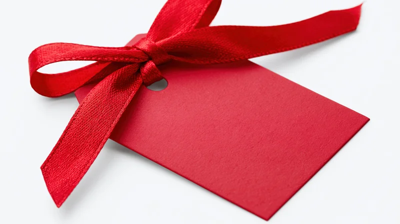 Red gift tag with satin ribbon bow on white background