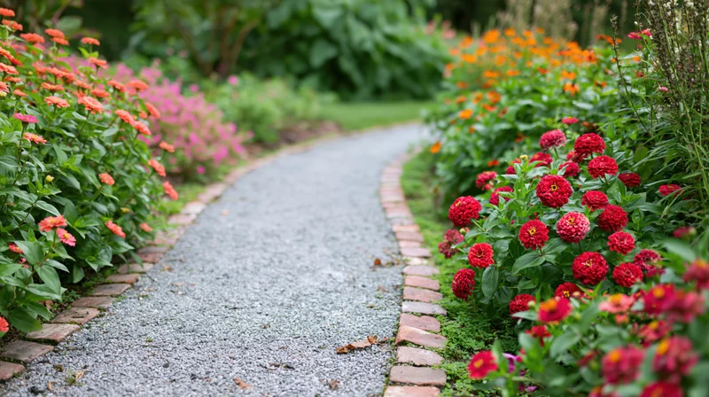 Curved gravel garden path edged with brick borders flanked by blooming zinnias and green foliage