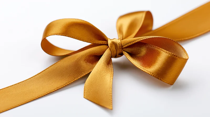 Gold satin ribbon tied in a decorative bow on white background