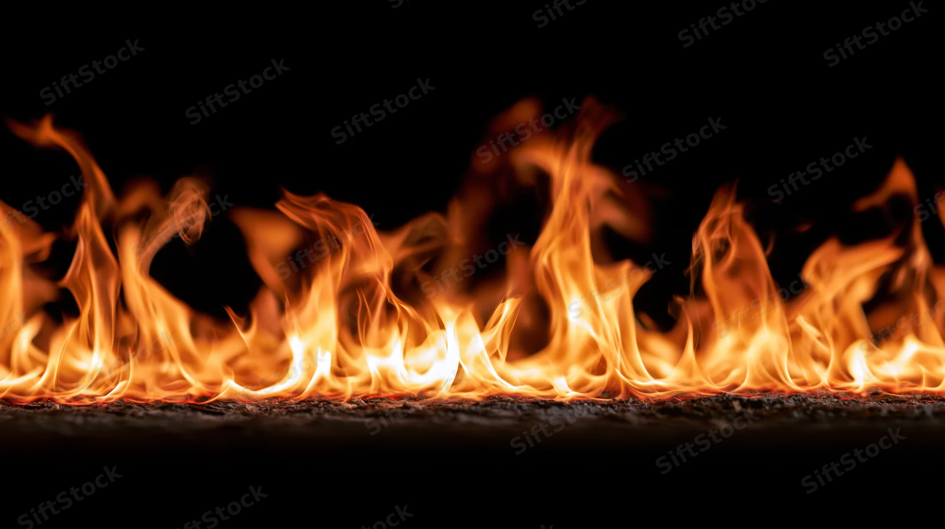 Horizontal band of flames burning across a dark surface