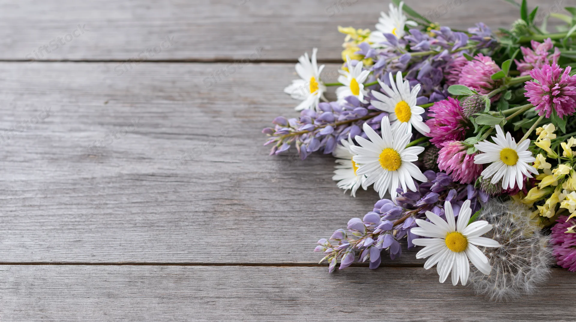 Wildflowers arranged on a gray wooden table with copyspace on the left