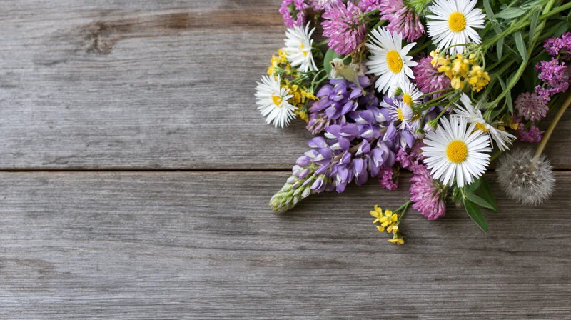 Wildflowers arranged on a weathered wooden surface with copyspace on the left