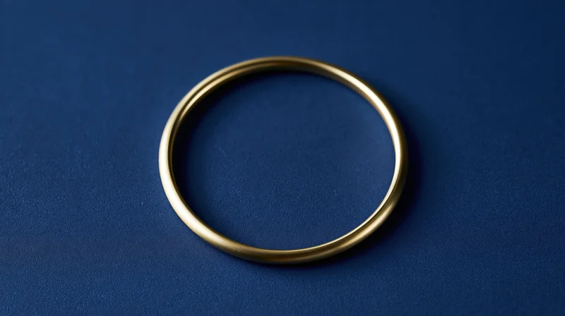 Polished gold ring centered on dark blue textured surface