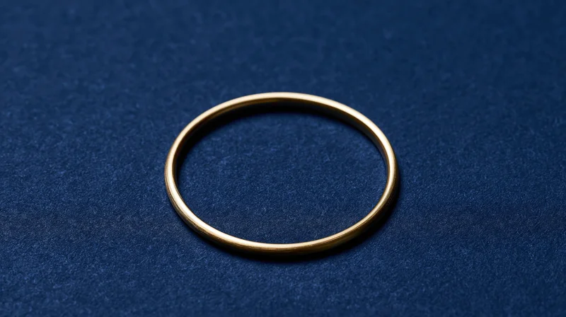 Polished gold ring centered on dark textured surface with copyspace