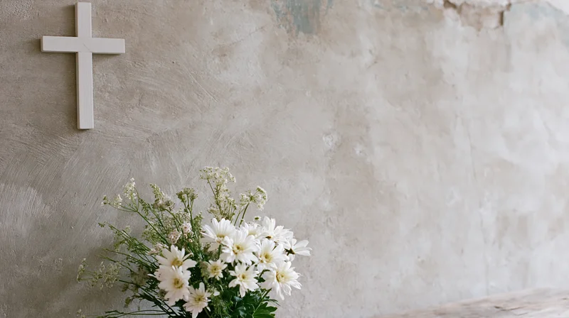 White christian cross on textured wall beside white flowers bouquet