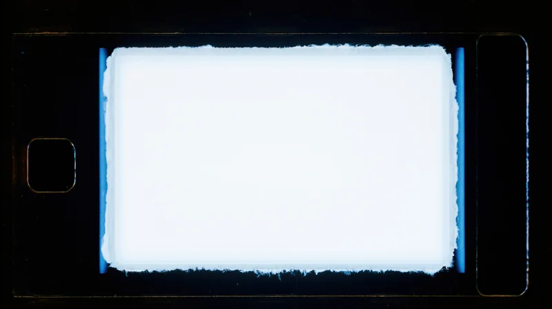 Blank 35mm film frame illuminated against dark background with blue edges and sprocket holes visible