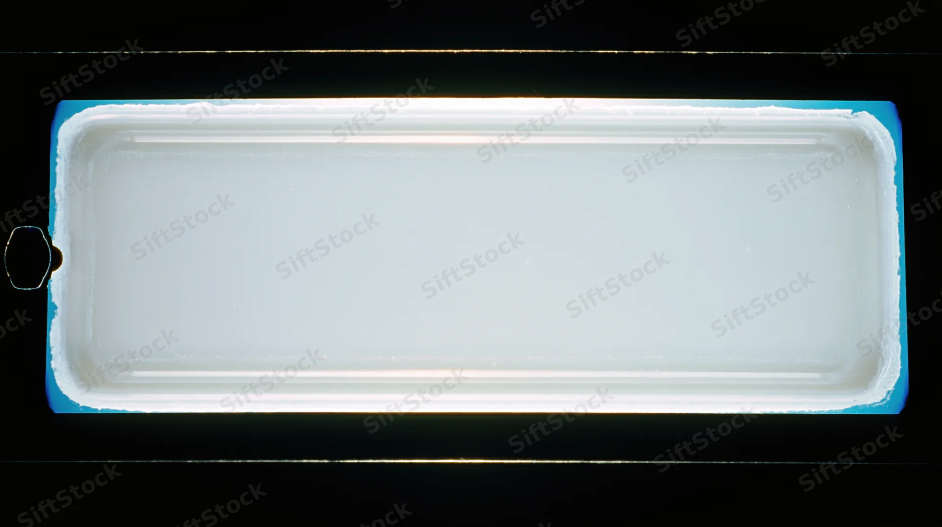 A blank 35mm film frame held up to a light source showing its translucent surface and blue border