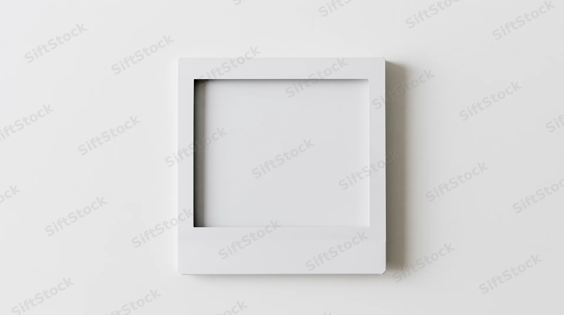 Blank white polaroid frame lying flat on a plain surface