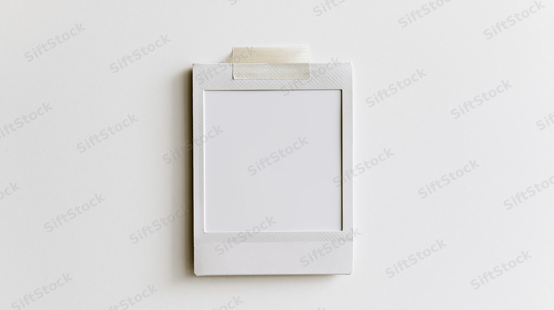 Blank white polaroid photo frame taped to a wall with copyspace