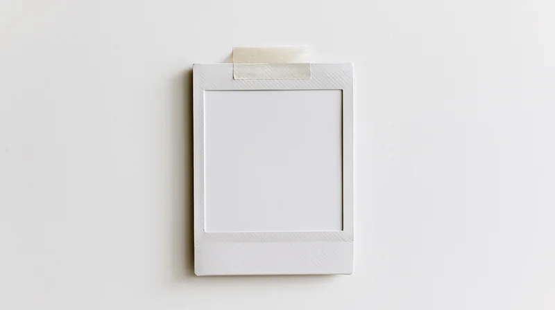 Blank white polaroid photo frame taped to a wall with copyspace