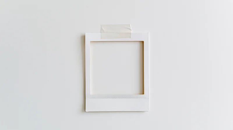 Blank white polaroid frame taped to a plain wall with copyspace