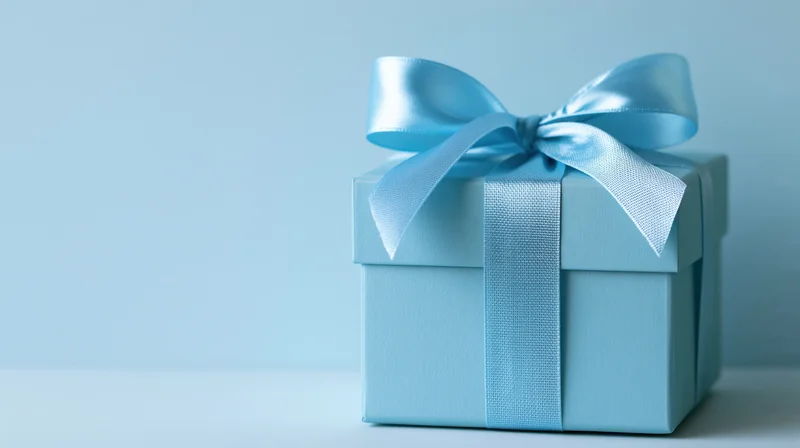 Light blue gift box with satin ribbon bow on plain surface