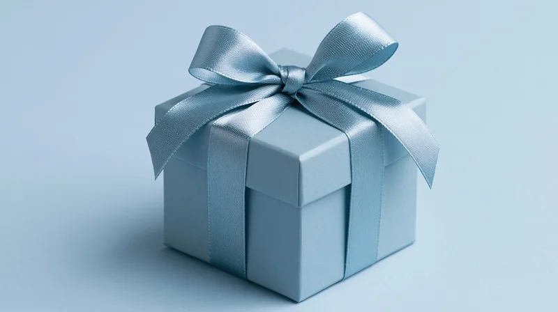 Blue gift box wrapped with satin ribbon bow on plain background