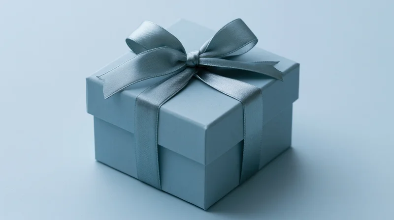Blue gift box with satin ribbon bow on plain surface