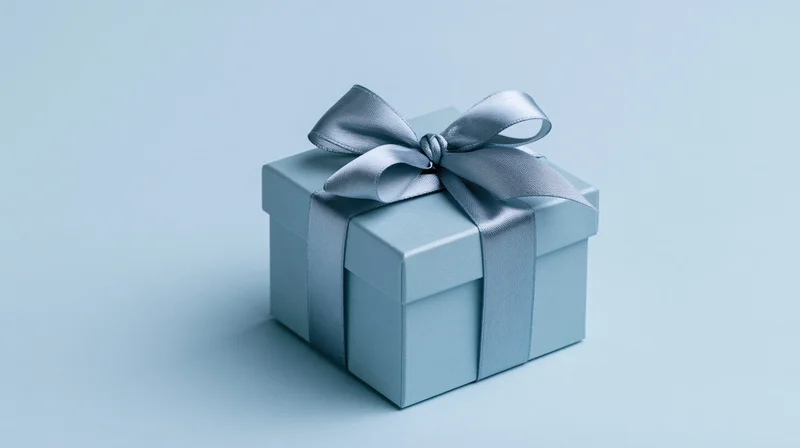 Blue gift box with satin ribbon bow on plain background