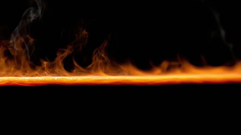 Horizontal line of fire burning across dark background with rising smoke