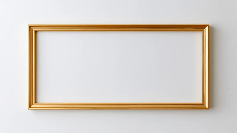 Gold rectangular picture frame hanging on white wall with blank interior
