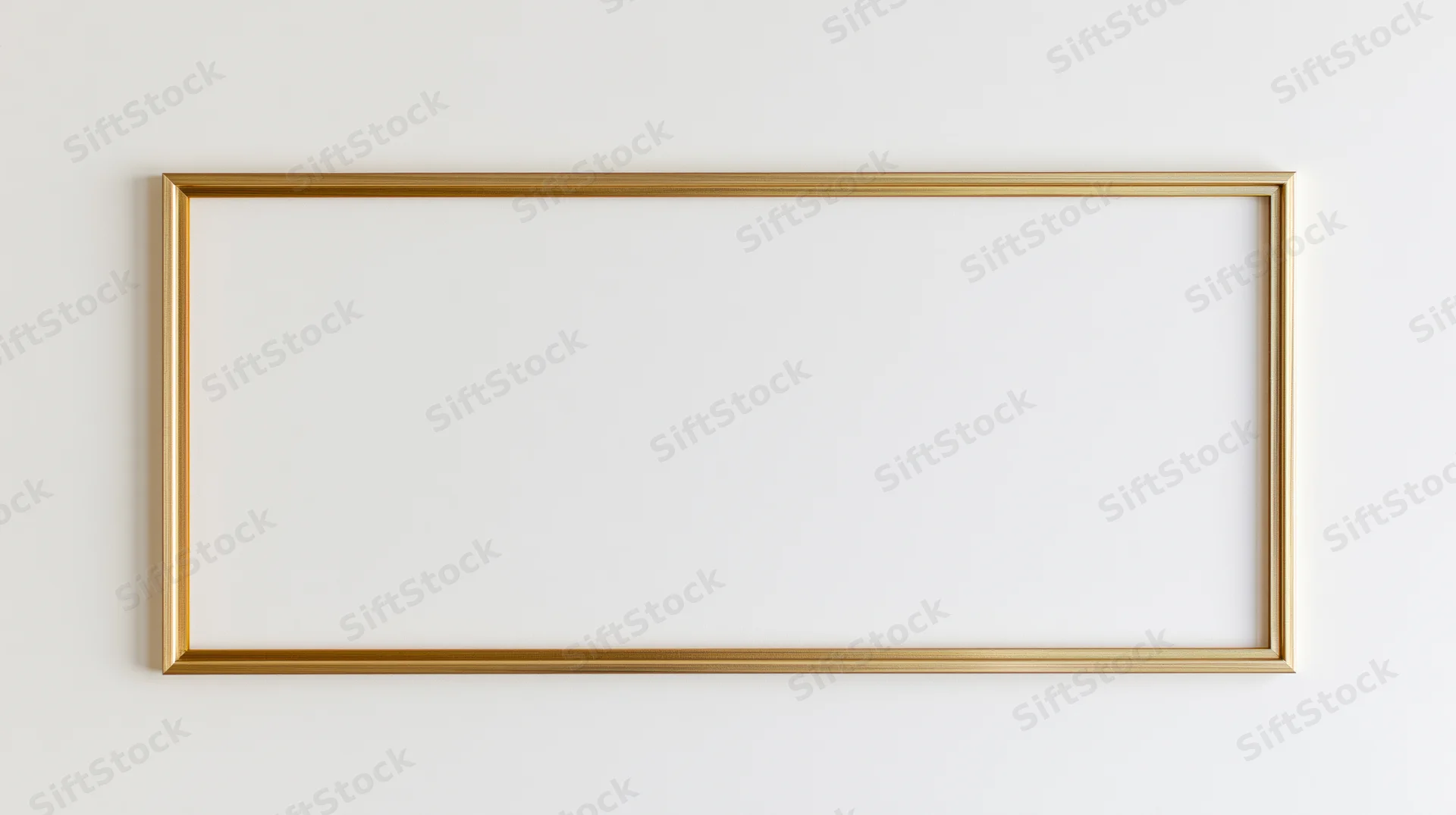 Thin gold rectangular frame hanging on a white wall with blank interior