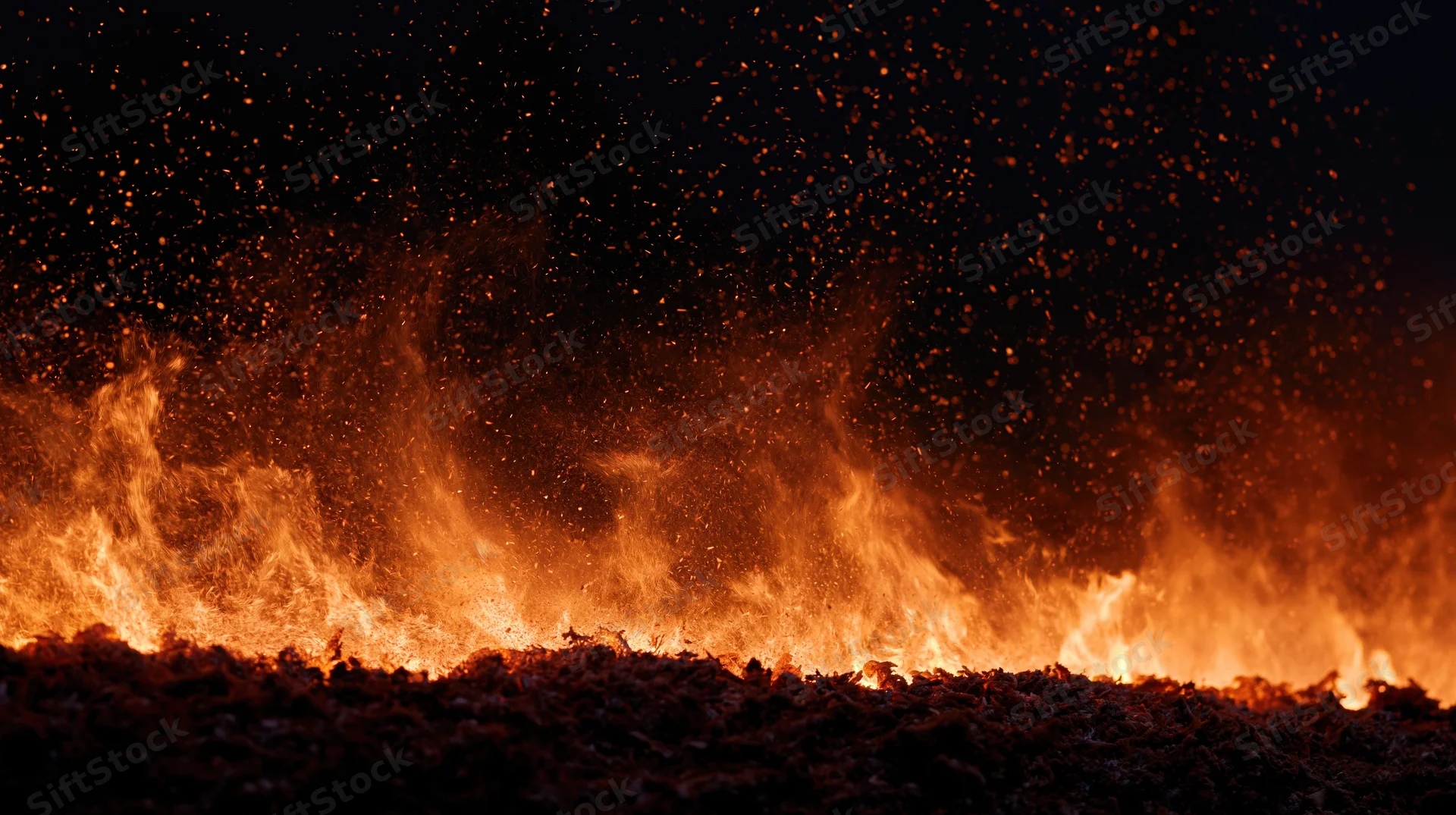 Intense fire burning along the bottom of the frame at night