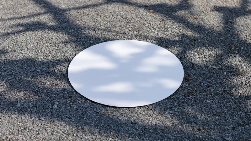 White oval sticker lying flat on rough asphalt pavement outdoors