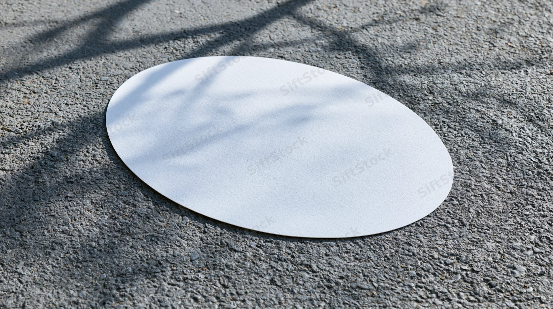 White oval decal lying flat on rough gray asphalt pavement outdoors
