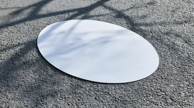 White oval decal lying flat on rough gray asphalt pavement outdoors