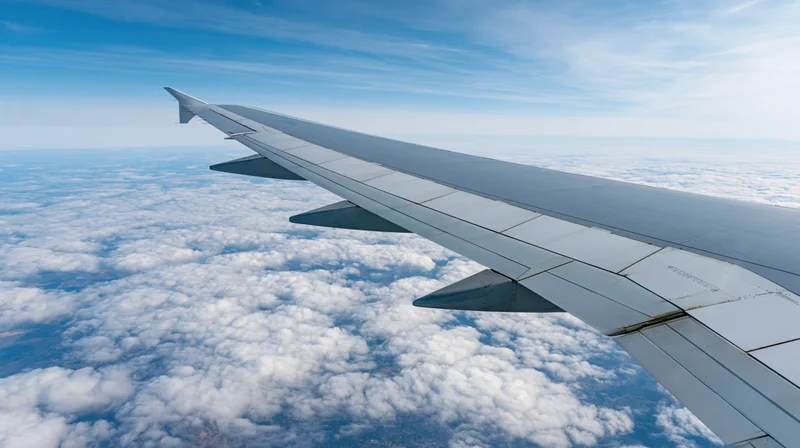 Airplane wing extending over a sea of clouds viewed from passenger window during cruising altitude flight