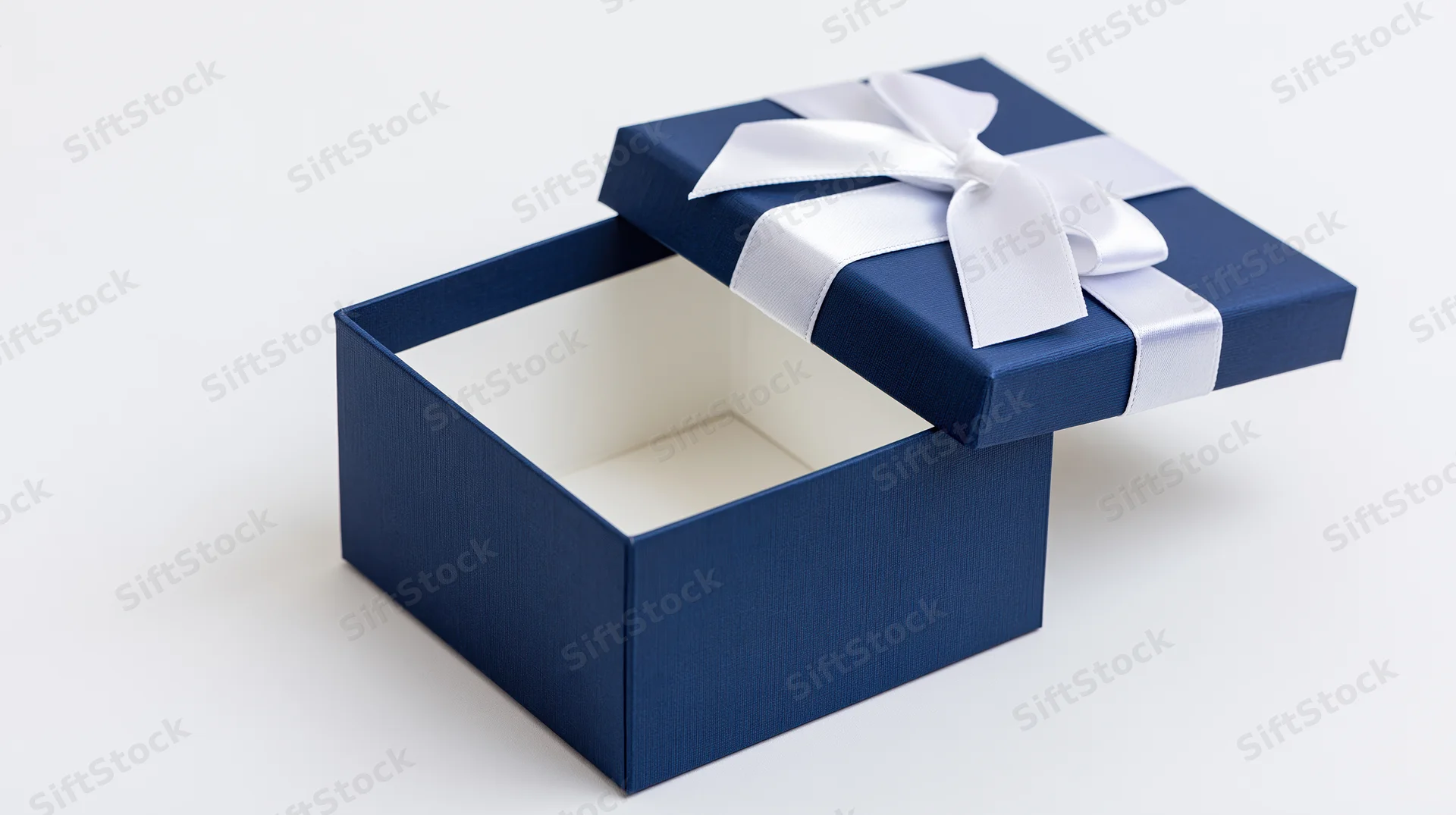 Open blue gift box with white ribbon bow and lid propped at angle on white background