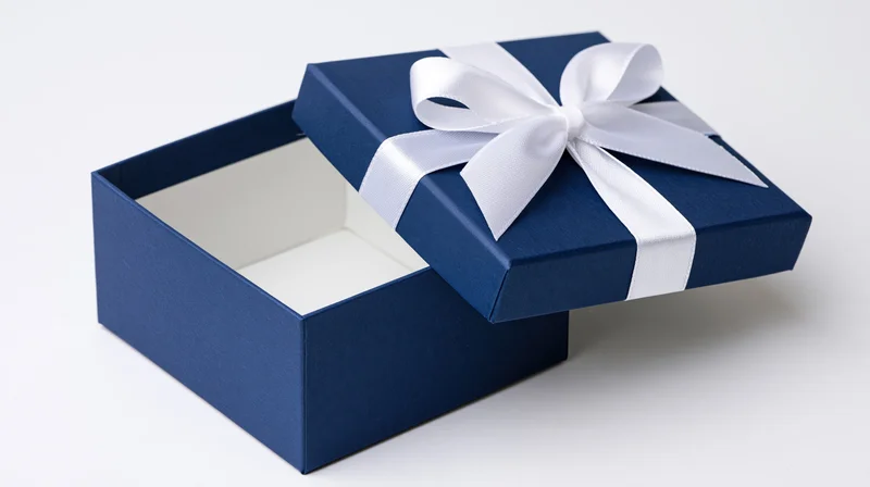 Open blue gift box with white ribbon bow on lid, empty interior visible, white background