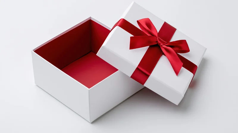 Open white gift box with red ribbon bow and lid beside it on white background