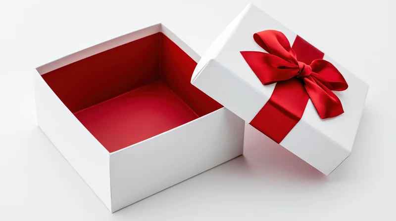Open white gift box with red ribbon bow and empty interior on white background