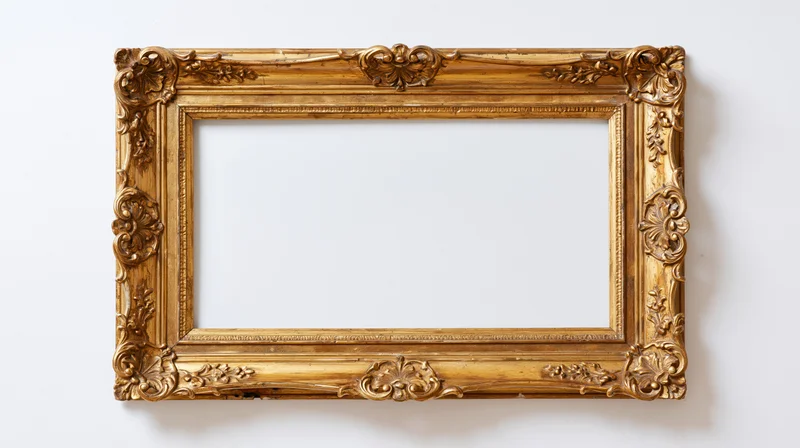 Ornate antique gold picture frame with baroque carved floral details hanging on white wall