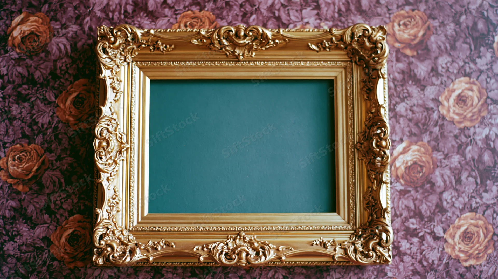 Ornate gold baroque frame with carved detailing mounted on floral wallpaper background