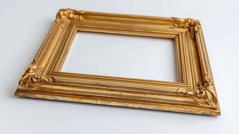 Ornate gold picture frame with carved corners lying flat on white background
