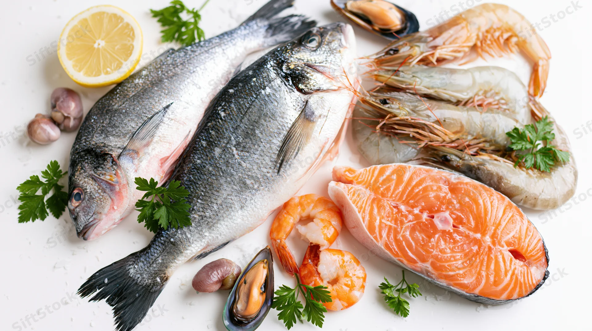 Assorted fresh raw seafood arranged on white surface with herbs and citrus