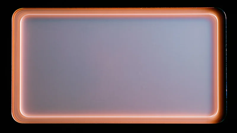 Blank overexposed analog film frame with glowing orange border on black background