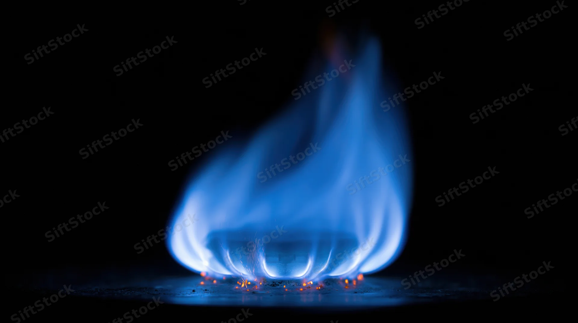 Blue gas flame burning in darkness isolated against black background