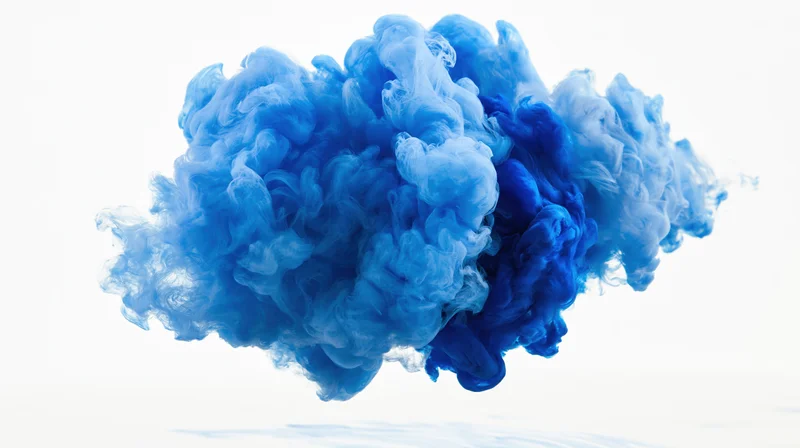 Blue ink dissolving and billowing in water against white background