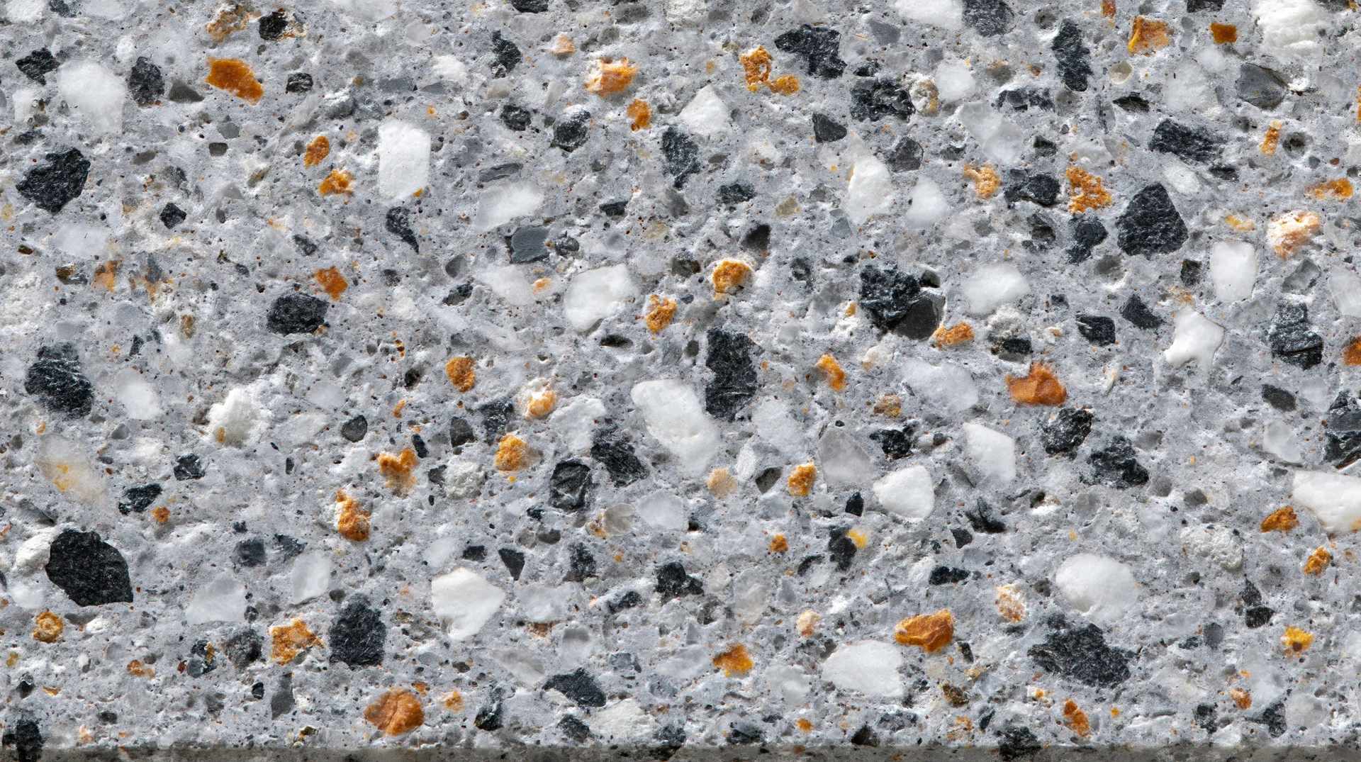 Close-up of polished terrazzo floor surface with gray matrix and black white orange aggregate specks