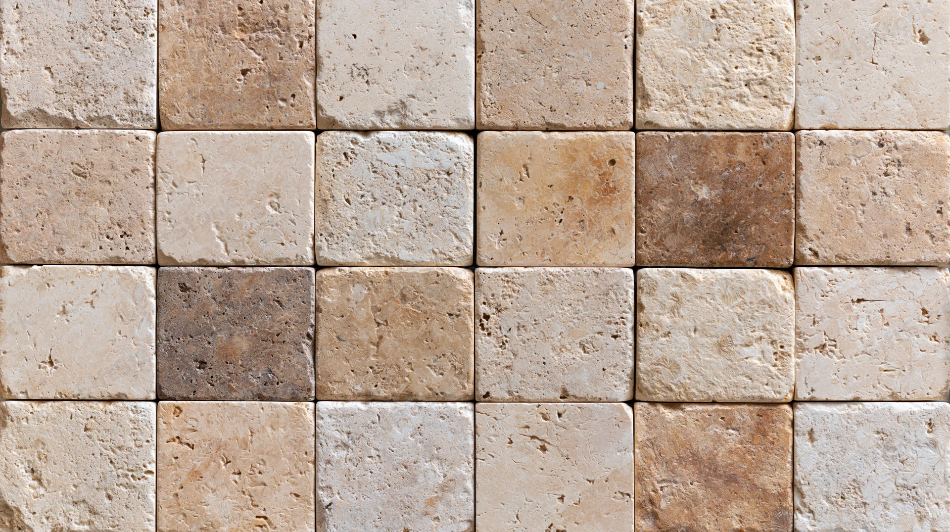 Close-up of travertine stone tiles arranged in a grid pattern on a wall